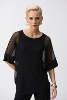 Close-up front view of the black mesh cocoon top, highlighting the sheer dolman sleeves and silky knit panel.