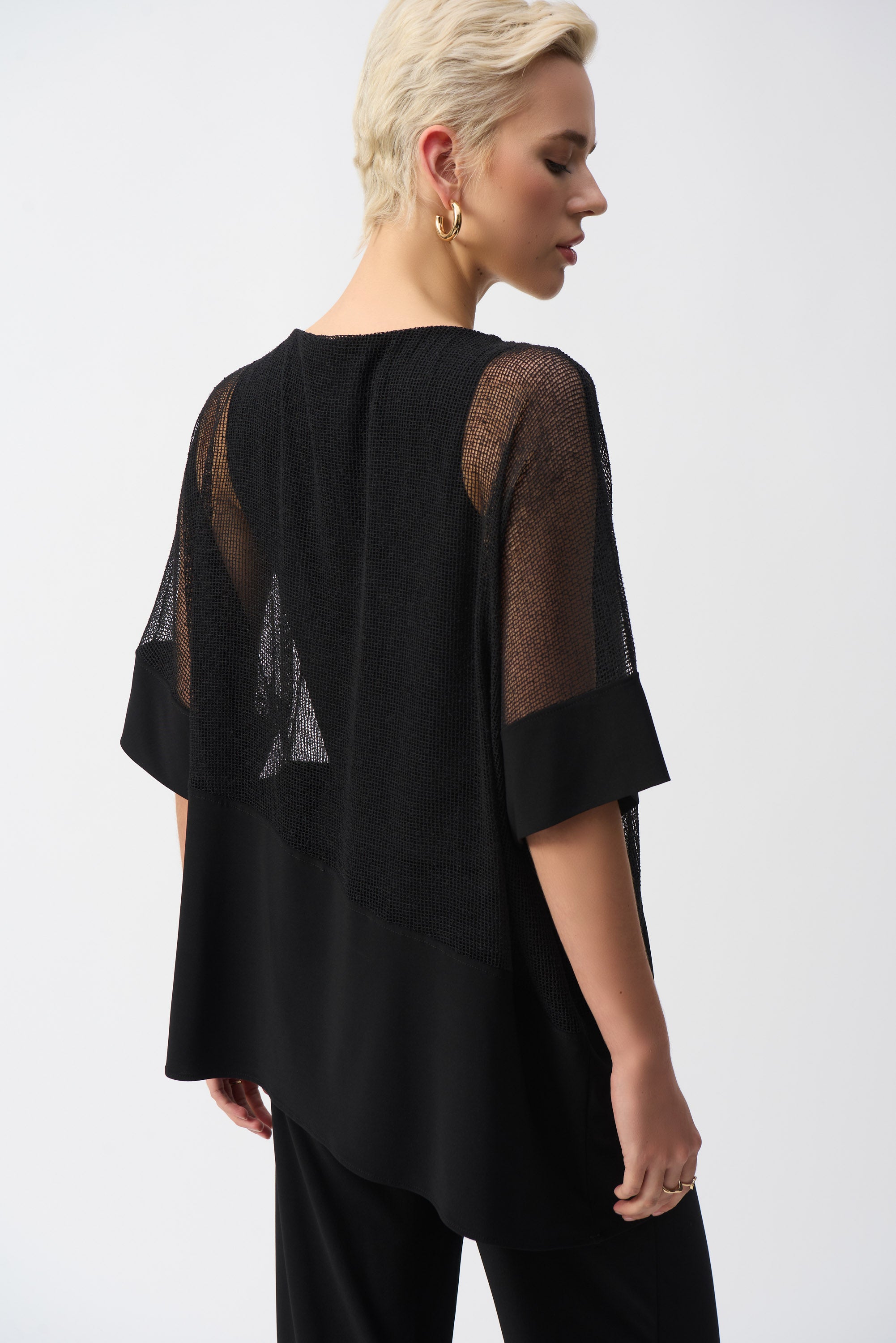 Rear view of the black cocoon top showcasing the sheer mesh back and relaxed silhouette.
