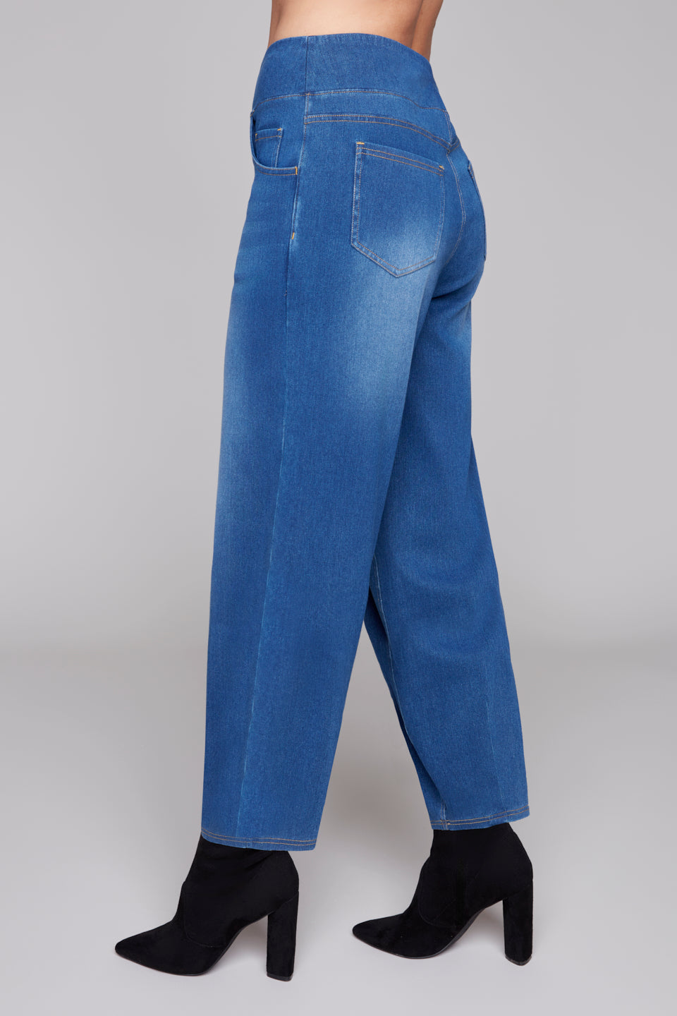 Side View of pull on Blue jeans worn by a person on a plain background