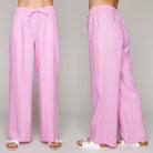 Woman wearing pink wide-leg linen pants with drawstring waist and white sandals