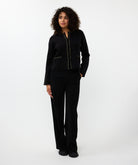 Woman wearing a black chain link cardigan with black pants on a white background