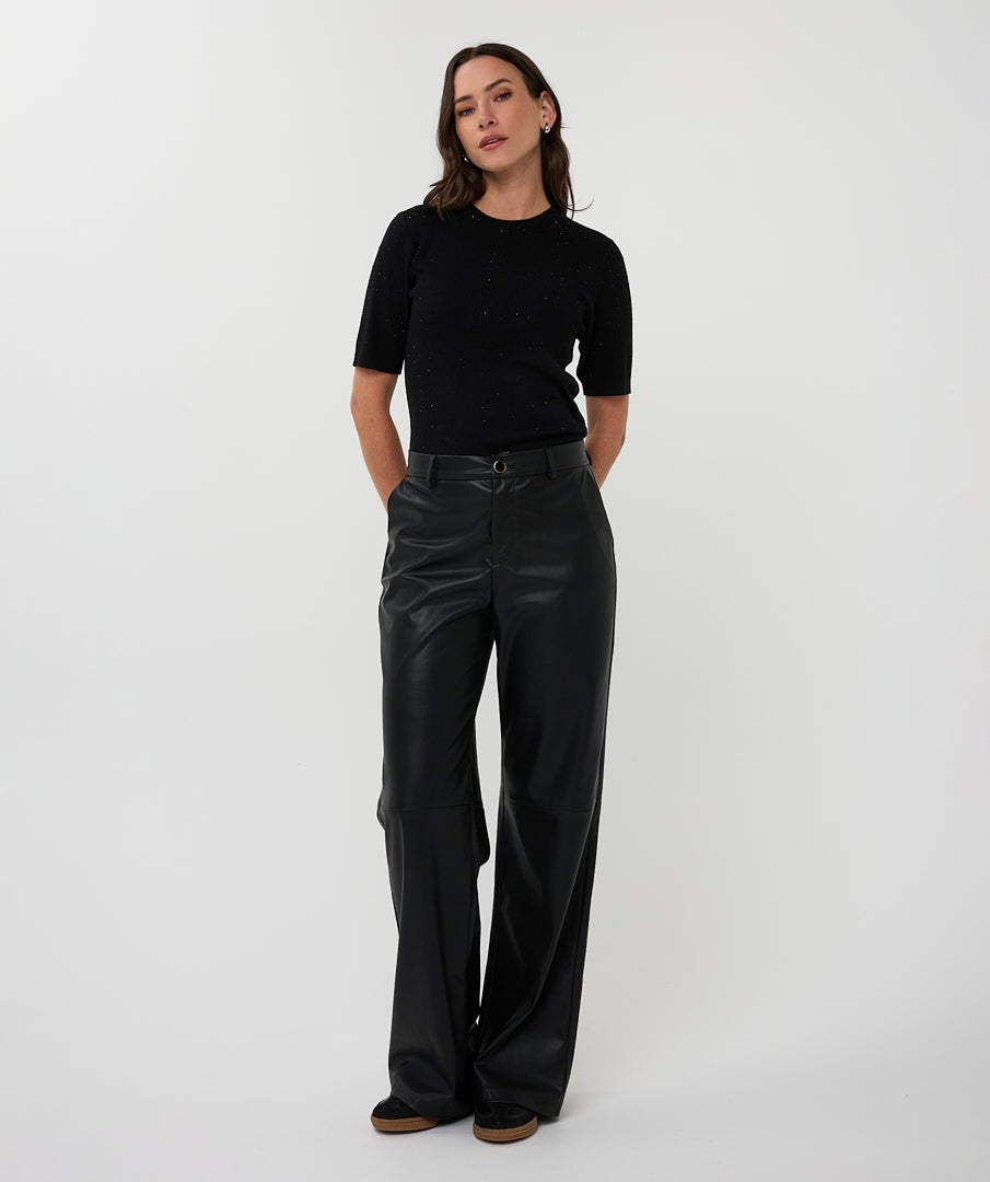 Person wearing black leather pants and a black top on a white background