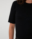Black short-sleeve top with speckled pattern on a plain background