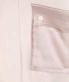 Close-up of a beige satin pocket with a button on a light background
