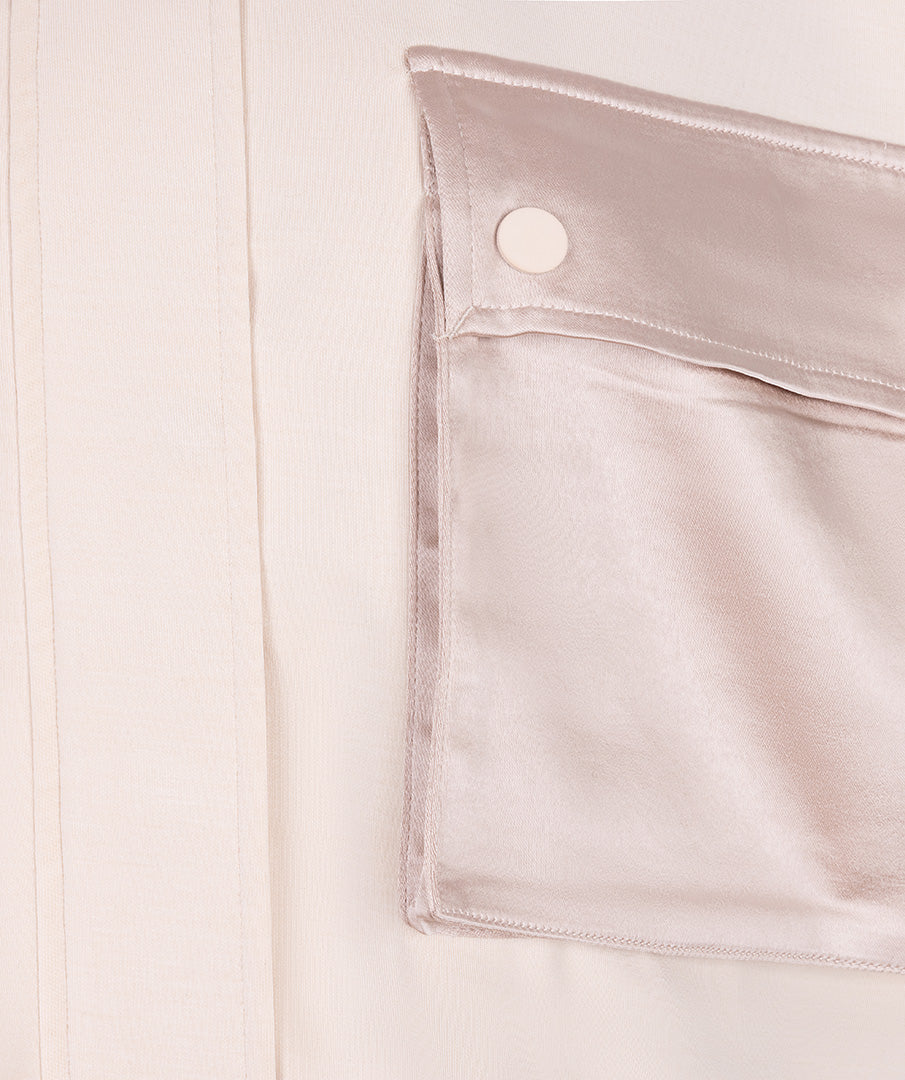 Close-up of a beige satin pocket with a button on a light background