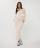 Woman wearing a beige outfit with a jacket and pants on a white background
