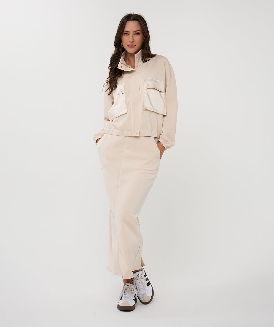 Woman wearing a beige outfit with a jacket and pants on a white background