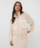 Woman wearing a beige jacket and pants on a white background