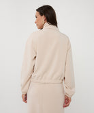 Back View of Woman wearing a beige jacket and skirt set on a white background