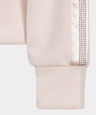 Close-up of a beige garment with decorative trim on a white background
