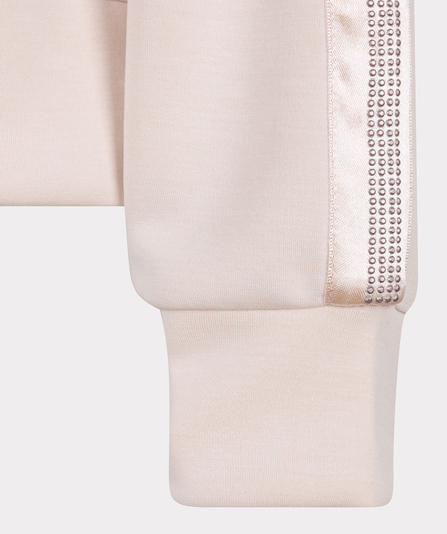 Close-up of a beige garment with decorative trim on a white background
