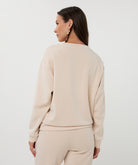 Back View of Woman wearing a beige outfit against a white background