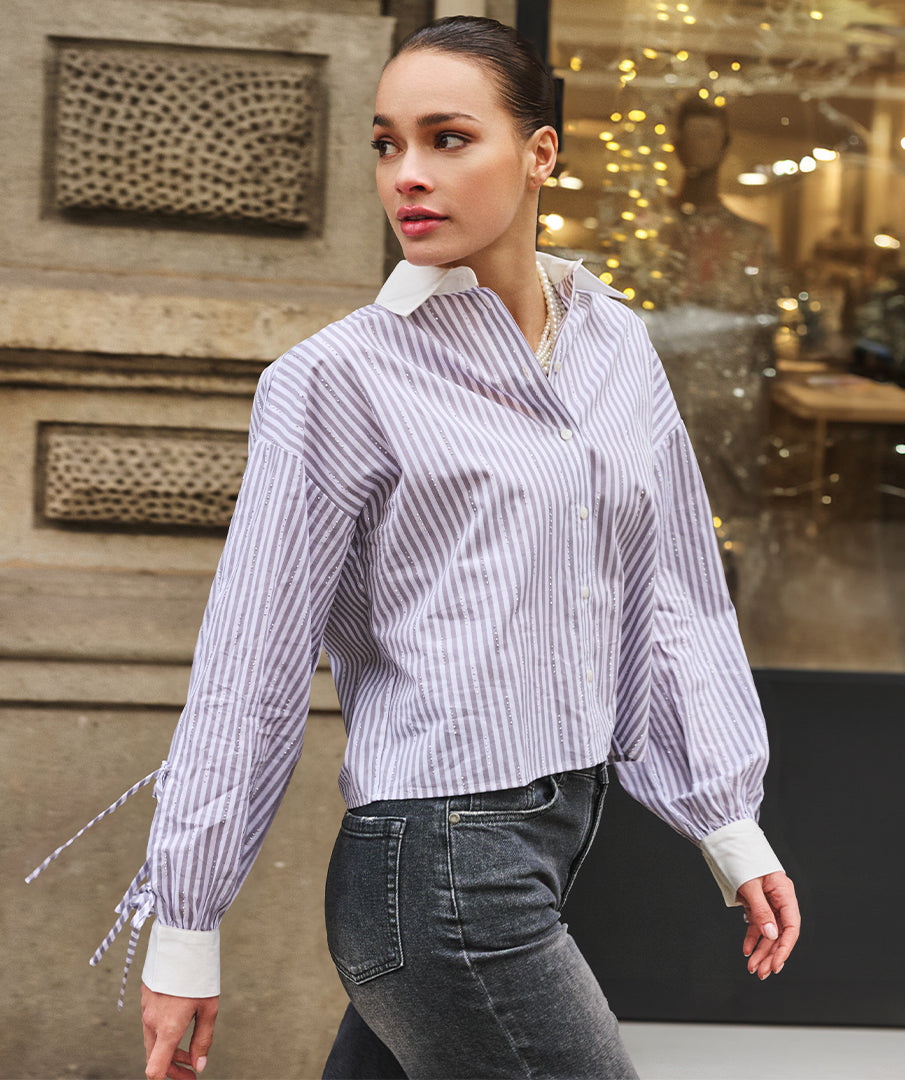 Woman wearing a striped shirt and jeans walking outdoors.