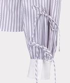 Close-up of a striped dress with a tie detail on a white background