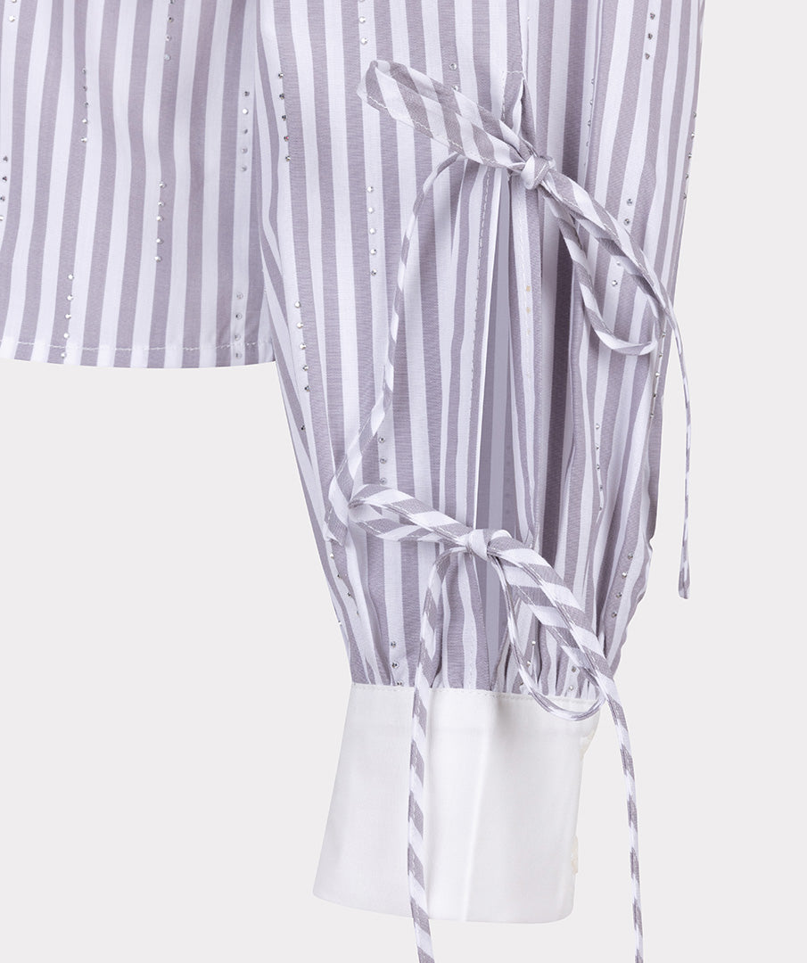 Close-up of a striped dress with a tie detail on a white background