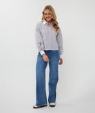 Woman wearing a striped shirt and blue jeans on a white background