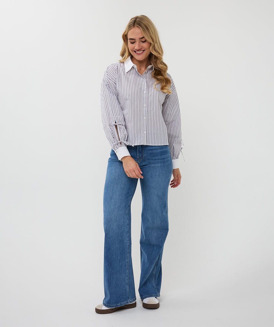 Woman wearing a striped shirt and blue jeans on a white background