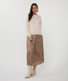 Woman wearing a cream sweater with crinkled skirt on a white background