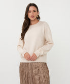 Woman wearing a beige sweater and skirt on a white background