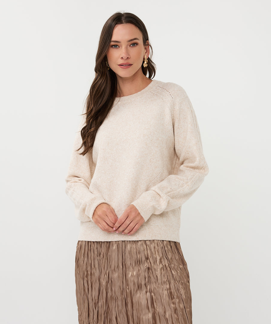 Woman wearing a beige sweater and skirt on a white background