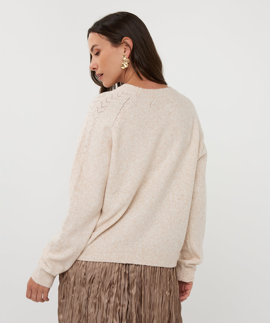 Woman wearing a beige sweater and brown pleated skirt on a white background, side back view 