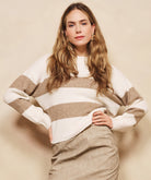 Woman wearing a striped sweater and beige pants against a beige background