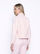 Back view of the light pink embroidered denim jacket, showing the clean yoke and subtle structure, styled with matching pink jeans.