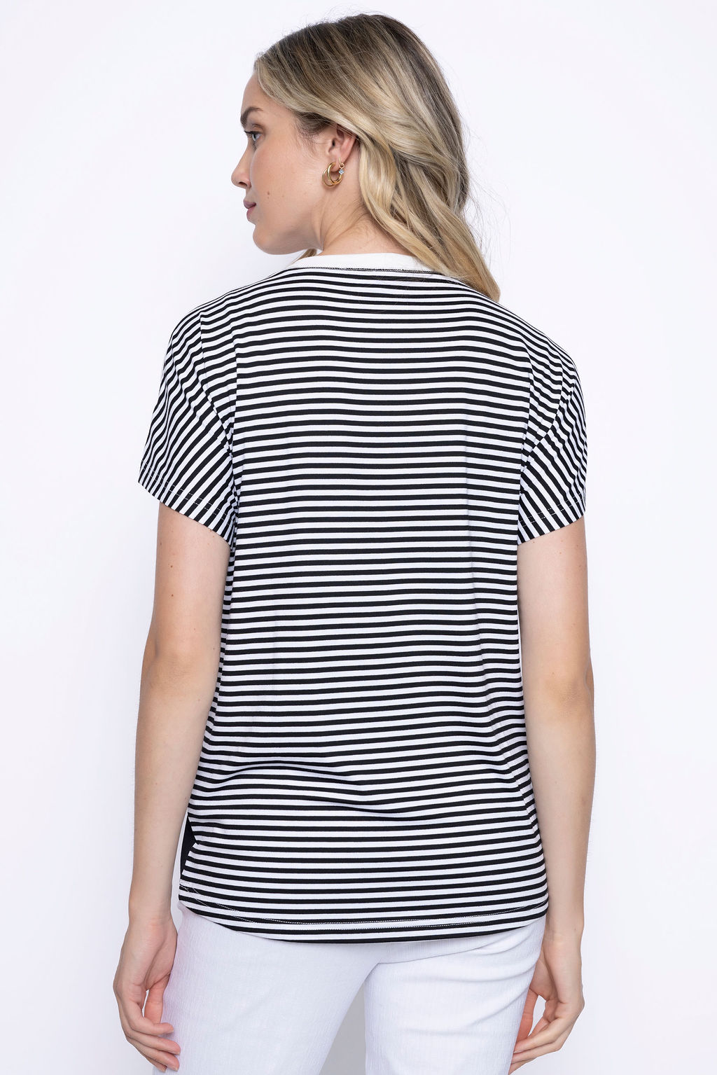 Back view of a woman wearing short sleeve printed top with black and white stripes with a relaxed fit, paired with white pants.