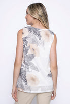 Back view of a woman wearing a sleeveless V-neck printed tank top in light khaki with neutral-toned floral and abstract prints.