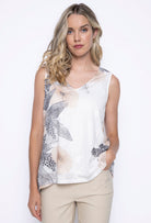 Woman wearing a sleeveless V-neck printed tank top in light khaki with soft neutral floral and abstract prints, paired with beige trousers.