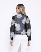 Woman shown from the back in the same sheer black embroidered jacket, highlighting the back detail and cropped length.