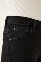 Detailed view of the front pocket and coin pocket on black jeans, highlighting stitching and rivet hardware.