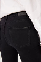 Close-up of black denim showing the back pocket, leather logo patch, and waistband seam detail.