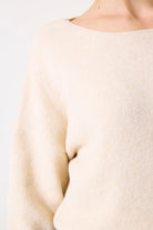 Close-up of the soft knit texture and neckline of the beige sweater.
