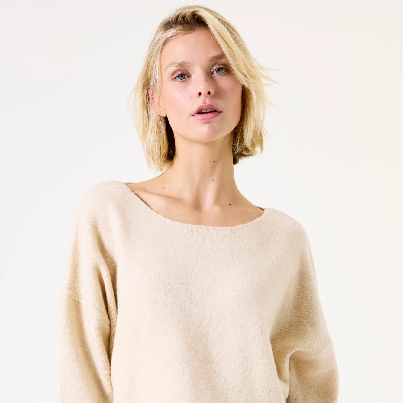 Woman wearing a beige sweater and leopard print pants on a white background