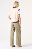 Back View of Woman wearing a beige vest and pants on a white background