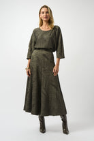 woman standing in a dark green top and long dark green skirt